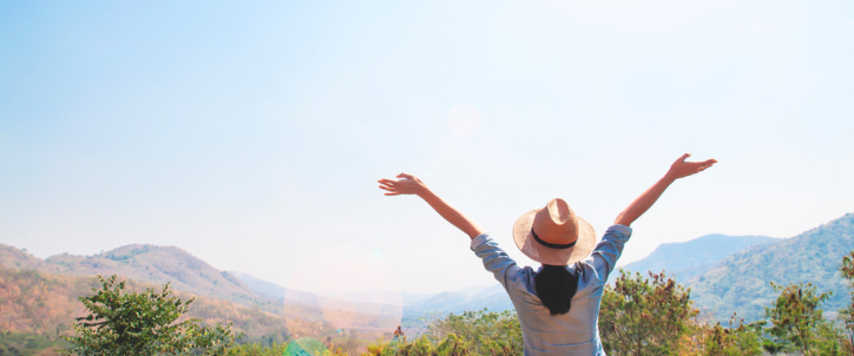 Rear View Of Woman With Arms Outstretched Standing Against Sky